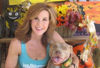 La actriz Linda Blair sonríe durante un evento mientras abraza a un perro rescatado.