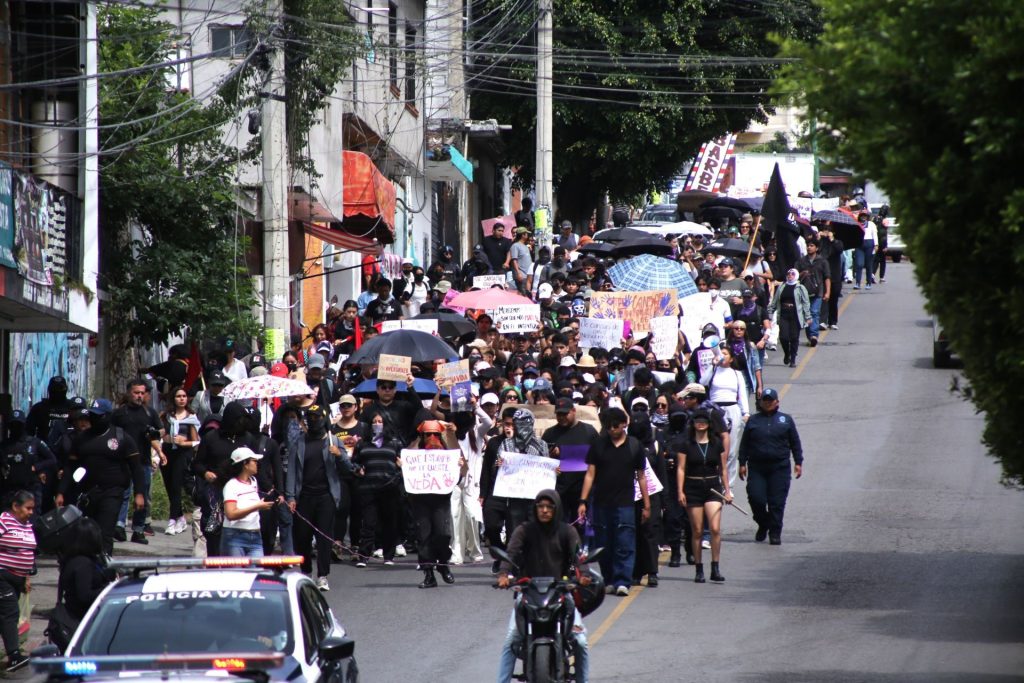 Cientos de estudiantes de la UAEM marchando por las calles de Cuernavaca portando pancartas de justicia.